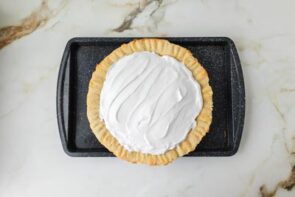 Lemon meringue pie topped with a thick layer of meringue before baking or torching.
