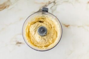 Pie crust dough being mixed in a food processor until a smooth dough forms.
