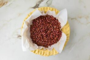 Pie weights made from dried beans lining a parchment-covered pie crust for blind baking.