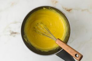 Homemade lemon curd cooking in a saucepan until thick and smooth.
