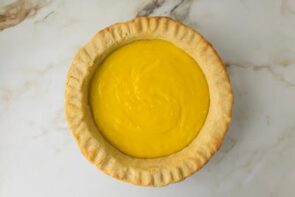 Baked pie crust filled with vibrant homemade lemon curd for lemon meringue pie.