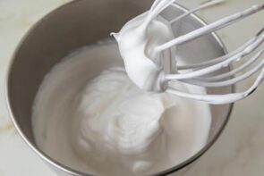 Glossy meringue whipped to stiff peaks in a stand mixer bowl.