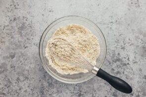 A whisk on top of mixed dry ingredients.