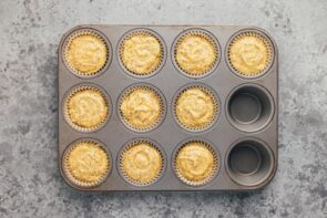 Muffin batter filled in muffin liners in a pan.