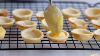 Filling baked mini crusts with thickened lemon curd.