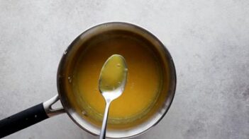 A spoon showing the thick consistency of lemon curd right after it is pulled from the stovetop.