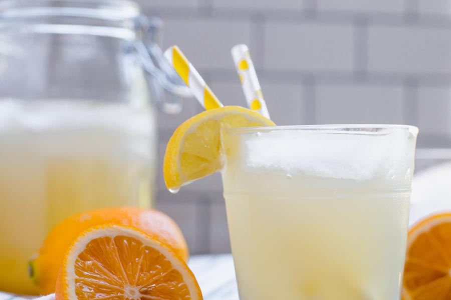lemonade with straws and a slice of lemon hanging off