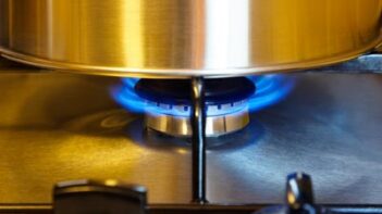 A sauce pan over a gas burner on a stove top.