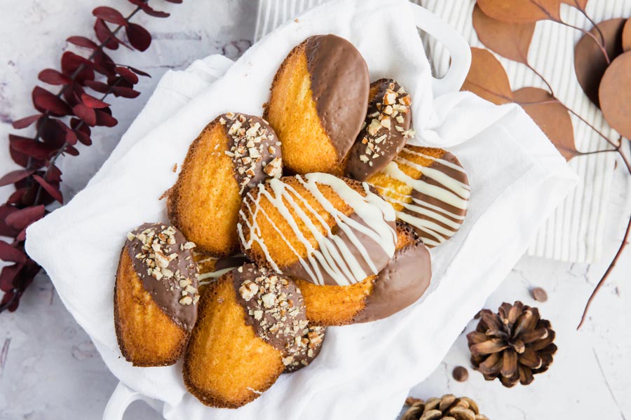 cookies in a bowl on top of a towel next to pine cones and leaves