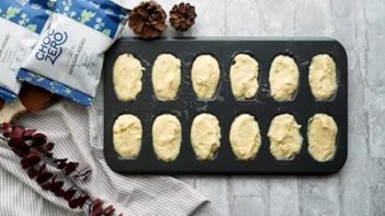 cookie batter filled in a madeleine pan with chocolate near by