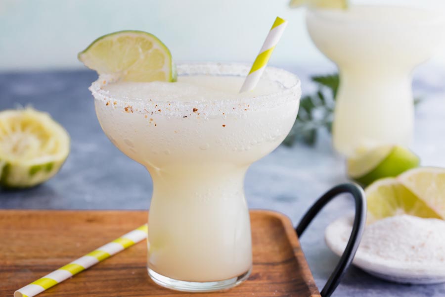 a frozen margarita with salt along the rim and stripped green straws