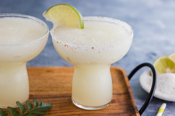 two blended margaritas with a lime in the glass