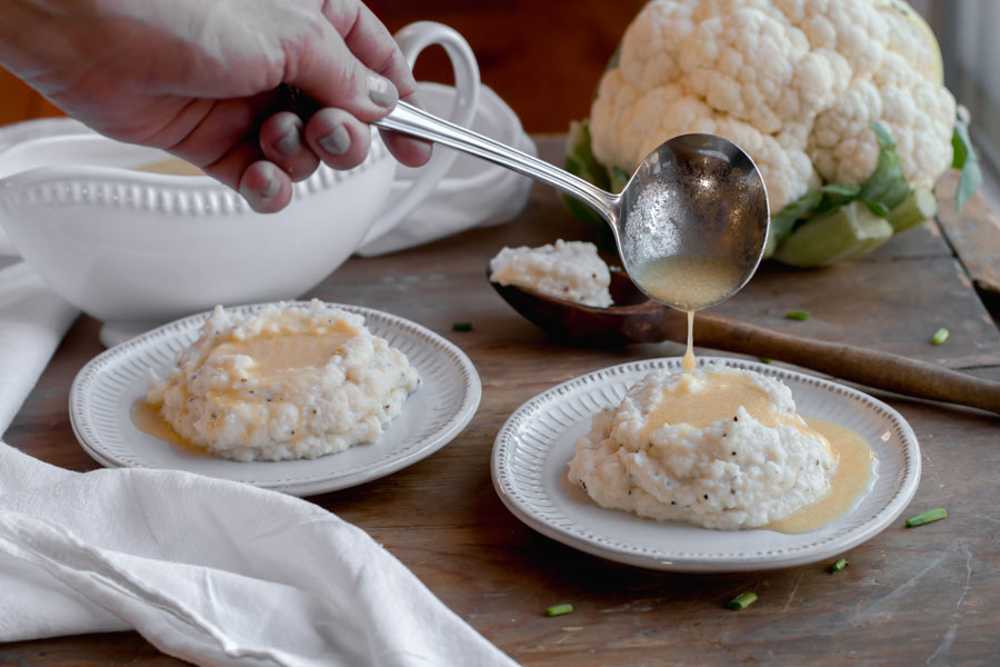 pouring gravey on keto mashed cauliflower