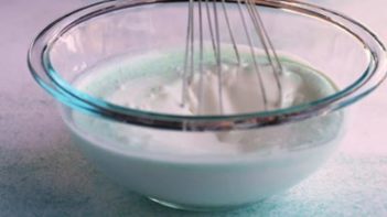 whisking green ice cream mixture with a whisk in a bowl