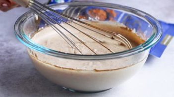 whisking an ice cream mixture in a large bowl with a wire whisk