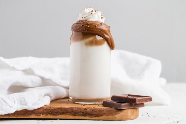 spooning whipped coffee layer onto cold glasses of nut milk