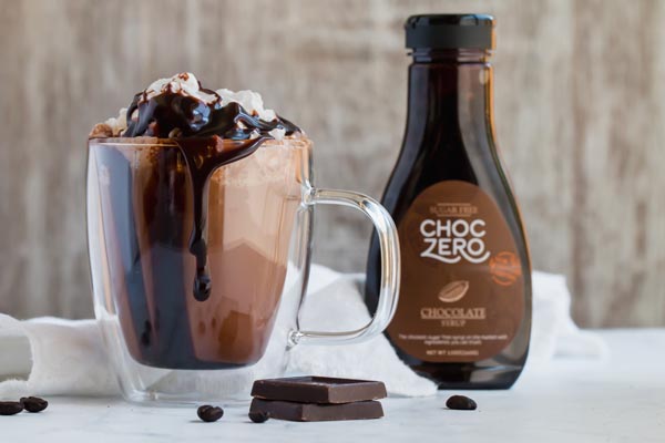 ChocZero Chocolate syrup next to overflowing glass mug with whipped cream