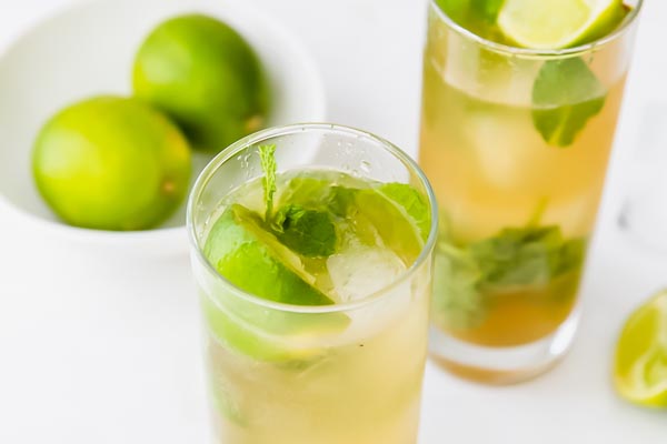 a lime wedge and mint leaf on top a mojito cocktail glass