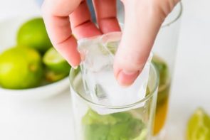 dropping an ice cube into a drink glass