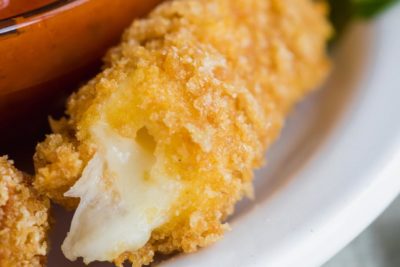 close up of a crispy keto cheese stick with mozzarella oozing out