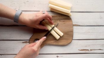 slicing mozzarella cheese sticks in half