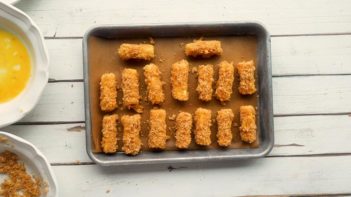 coated cheese sticks on a baking tray