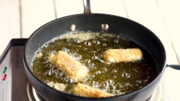 mozzarella sticks frying in a skillet with oil
