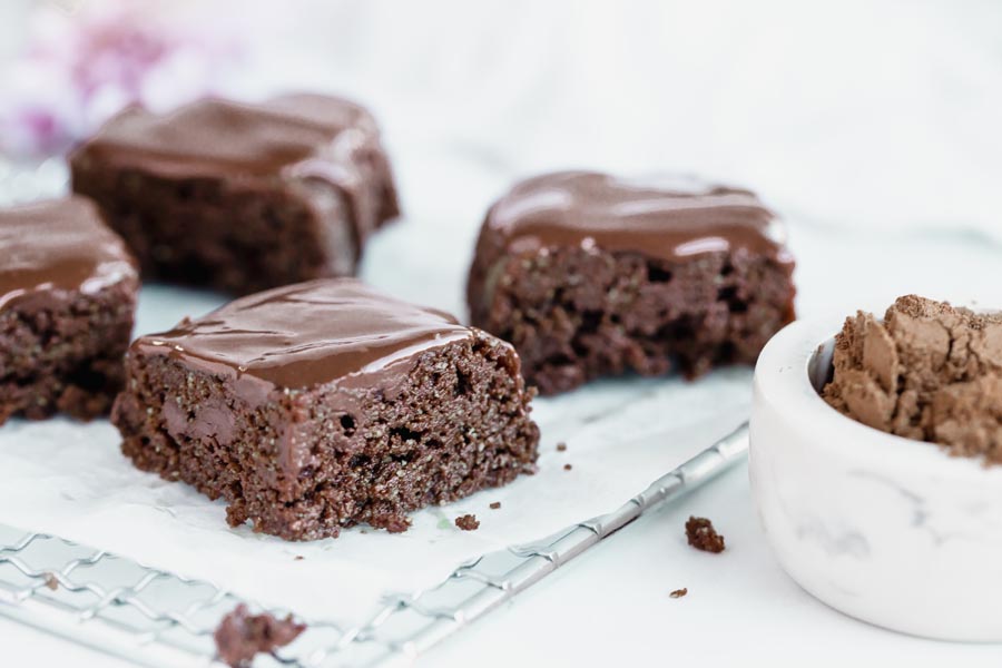 moist brownies on a parchment lined rack iced with chocolate