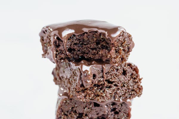 three small brownies stacked on each other covered in melted chocolate icing