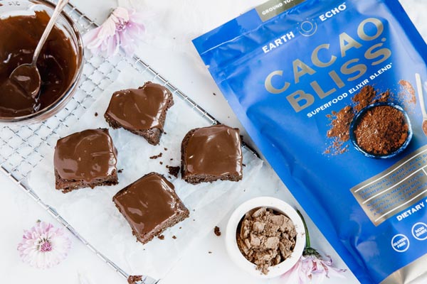 a bag of cacao bliss next to four brownie bites covered in chocolate