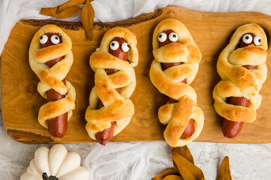 halloween lunch of keto bagel dogs wrapped like a mummy on a wooden board