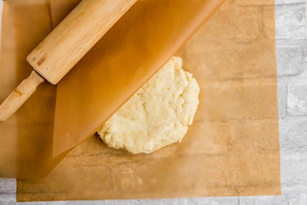 a ball of fathead dough in between two sheets of parchment paper