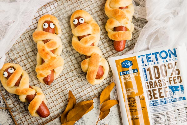 mummy dogs on a rusty wire rack with a package of hot dogs