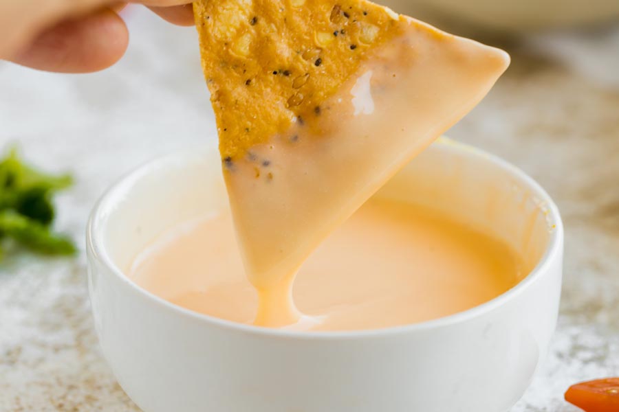 dipping a tortilla chip into queso