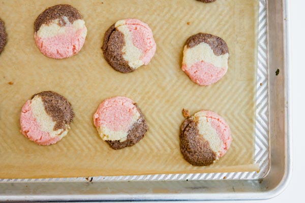 three keto cookies dough flavors of strawberry, vanilla and chocolate pressed together to form a cookies on a baking tray
