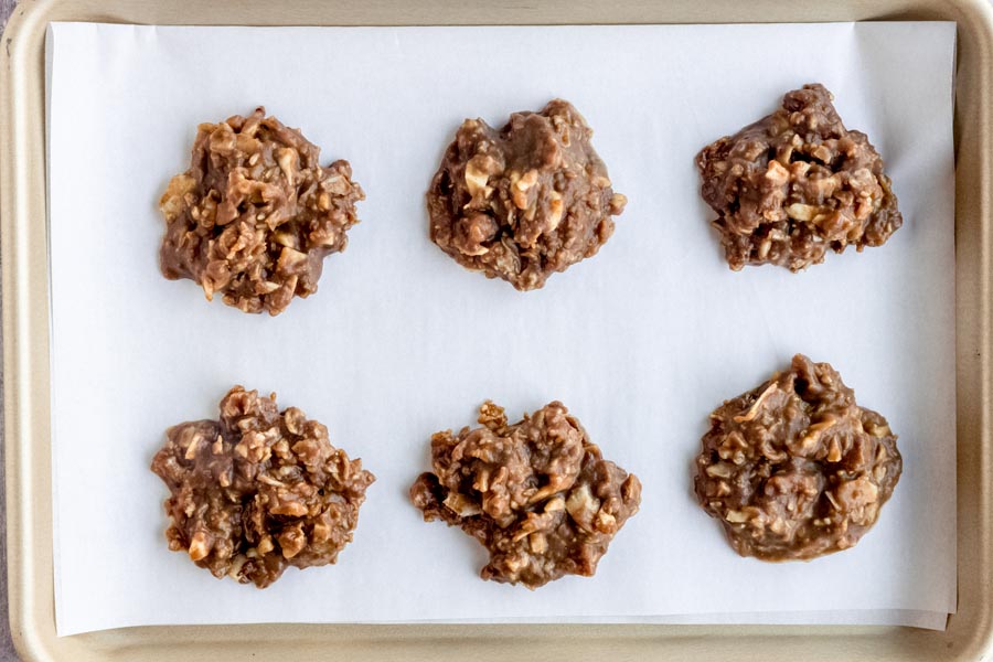 Six chocolate no bake keto cookies on a parchment lined baking tray.