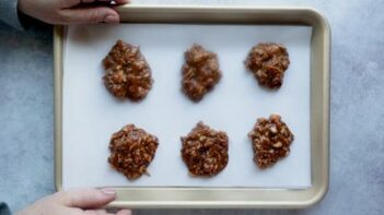 Holding a cookie tray with 6 no-bake cookies on it.