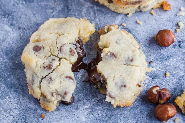 a cookie pulled apart with a creamy chocolate center and hazelnuts around