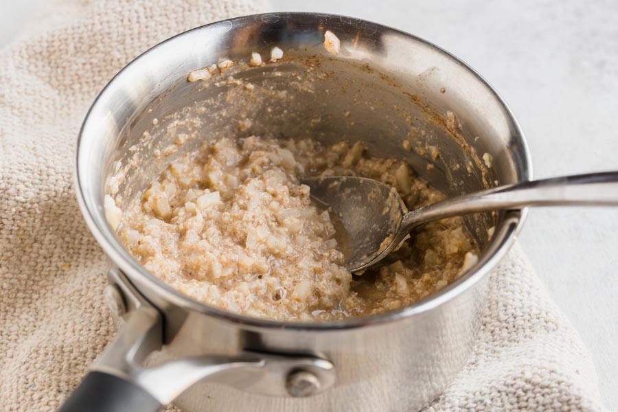 A small pot with cooked keto oatmeal inside mixed with cinnamon.