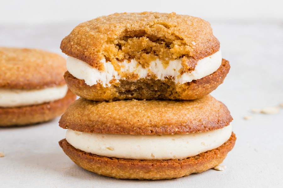 A stack of two oatmeal cream pies. The top pie has a bite taken out of it.