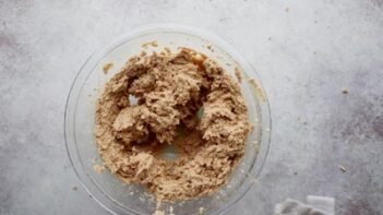 A clear glass bowl with oatmeal cookie dough inside.