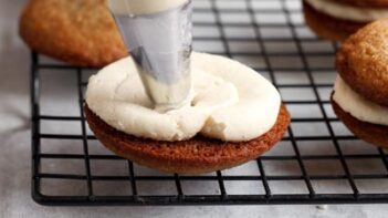 Piping cream filling on a bottom sandwich cookie.