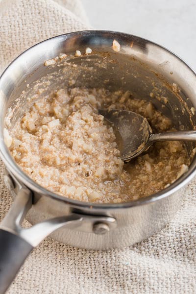A pot with thick oatmeal and a big spoon lies in the pot.