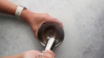 Hands grinding chia seeds with a mortal and pestle.