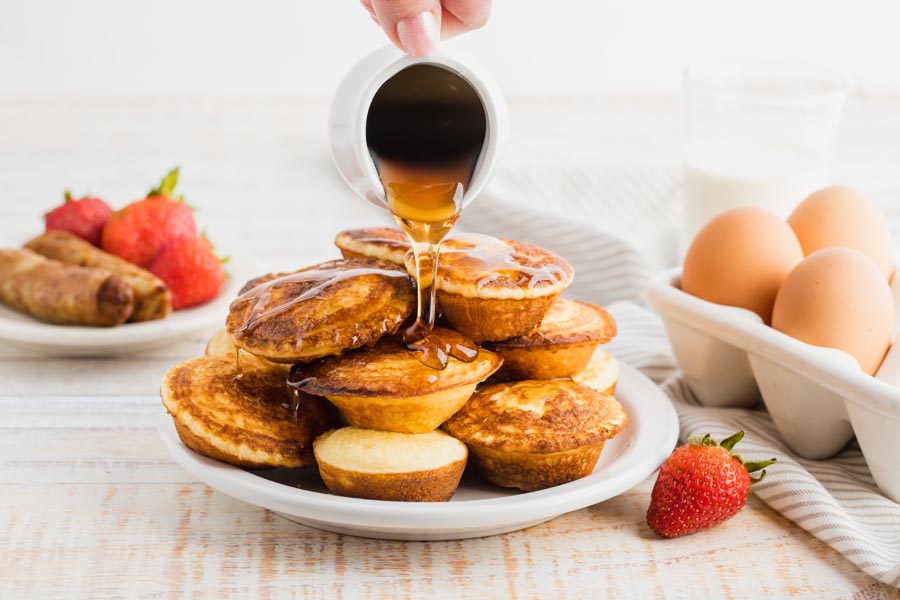 pouring syrup on top of a bunch of mini pies