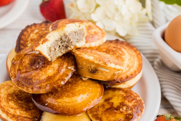 a mini pancake pie cut in half with sausage patty on the inside