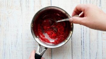 mixing a berry mixture in a saucepan with a spoon