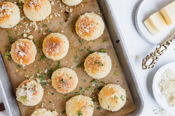 a tray of rolls with grated parm and fresh herbs on top
