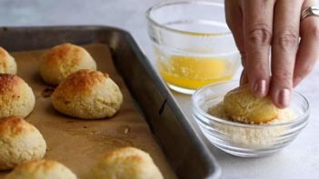 dipping a mini roll in some grated parmesan cheese