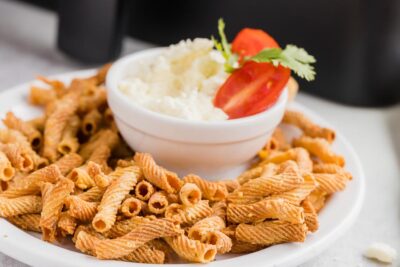 a plate with baked pasta chips on it next to a bowl of dip
